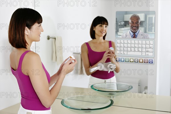 Mixed race woman using computer in mirror