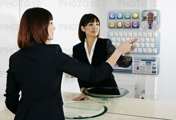 Mixed race businesswoman using computer in mirror