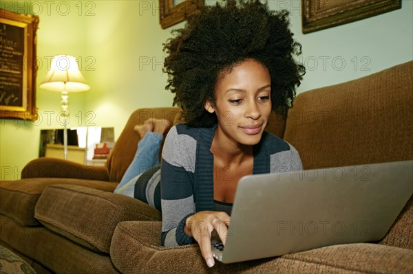 Mixed race woman using laptop on sofa