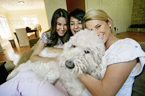 Women petting dog in kitchen