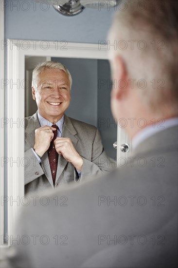 Businessman adjusting his tie in mirror