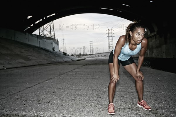 African American runner resting under overpass