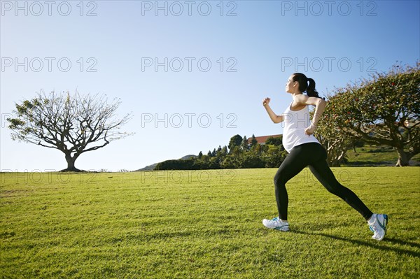 Pregnant mixed race woman jogging in field