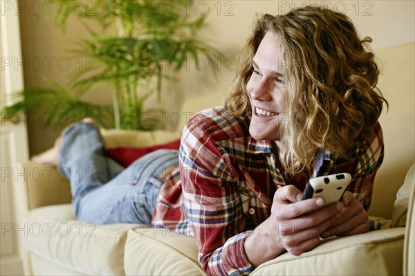 Caucasian man using cell phone on sofa