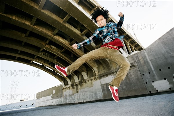 Asian man break dancing under overpass