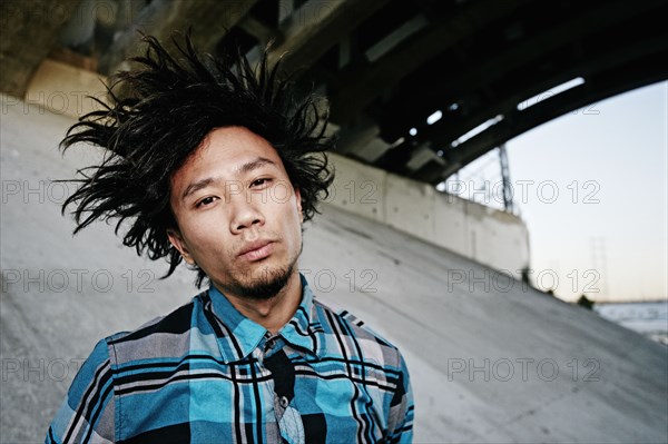 Asian man standing under overpass