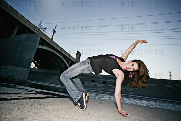 Caucasian woman break dancing under overpass