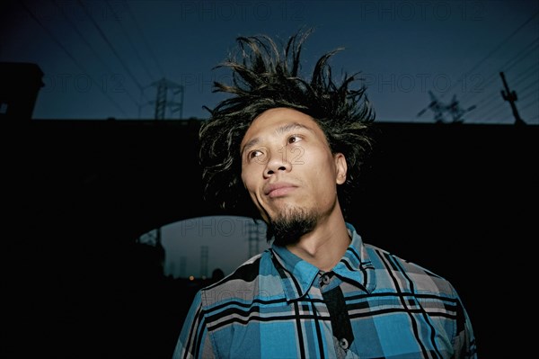 Asian man standing under overpass