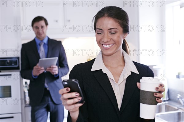 Mixed race businesswoman using tablet computer in kitchen