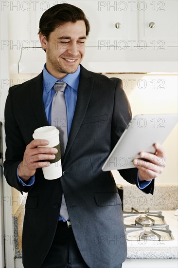 Caucasian businessman using tablet computer in kitchen