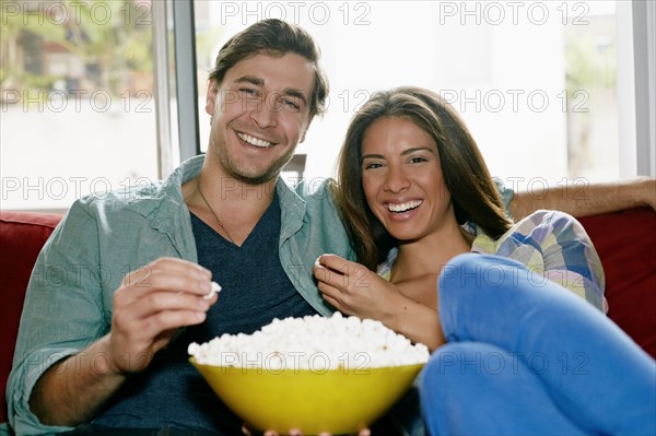 Couple eating popcorn on sofa