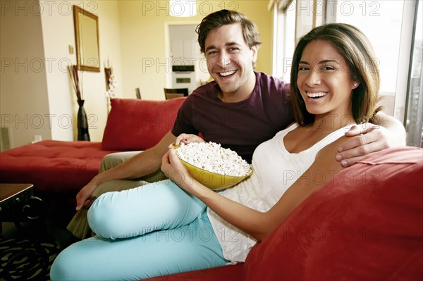 Couple eating popcorn on sofa