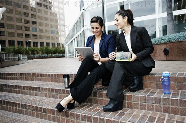 Businesswomen using tablet computer at lunch