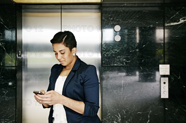 Hispanic businesswoman using cell phone