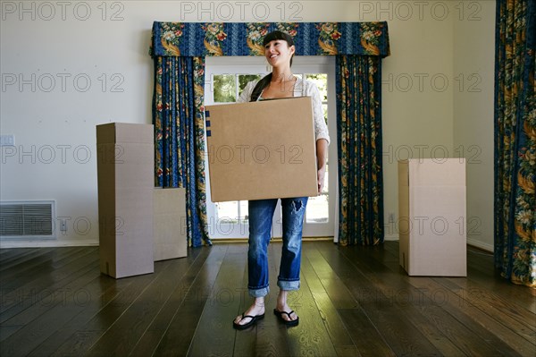 Mixed race woman carrying box in new home