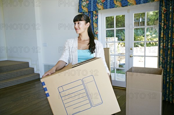 Mixed race woman carrying box in new home