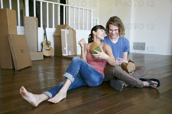 Couple eating take out food in new home