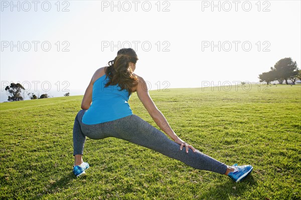 Mixed race woman stretching in park