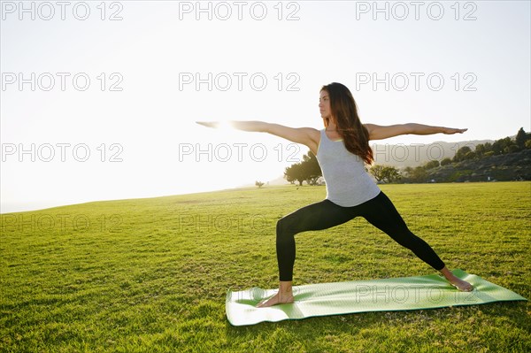 Mixed race woman practicing yoga in park