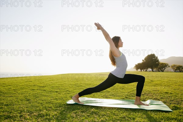 Mixed race woman practicing yoga in park