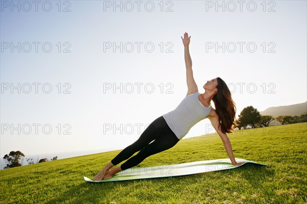 Mixed race woman practicing yoga in park