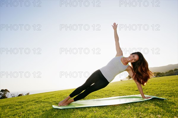 Mixed race woman practicing yoga in park