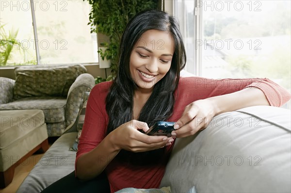 Indian woman using cell phone on sofa