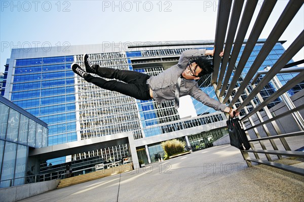 Asian businessman doing tricks on handrail