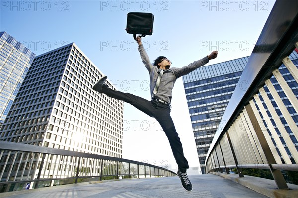 Asian businessman leaping on urban walkway