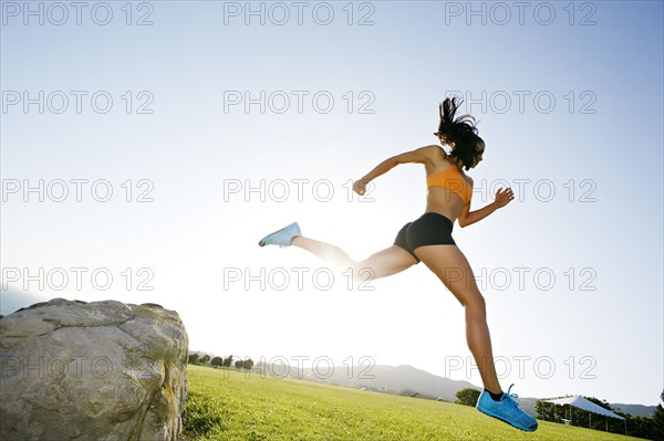 Hispanic woman running in rural landscape