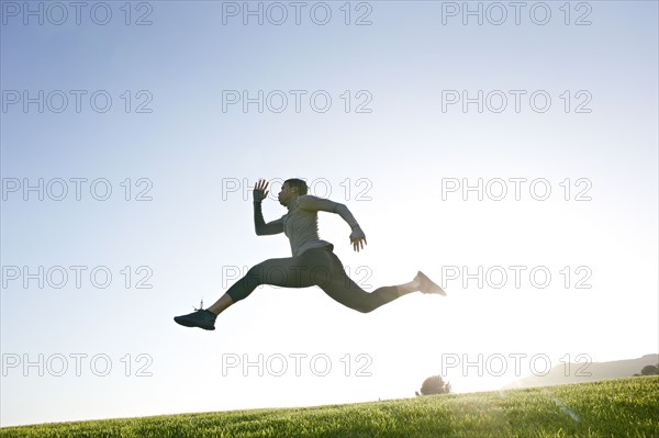 Black woman running in rural landscape
