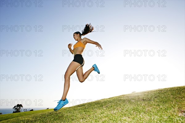 Hispanic woman running in rural landscape