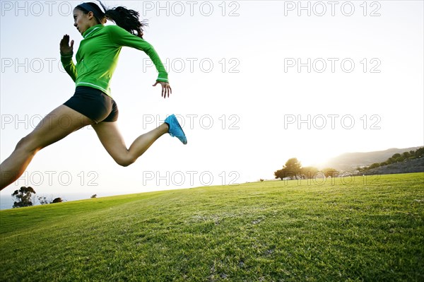 Hispanic woman running in rural landscape