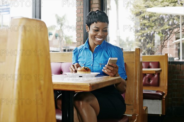 African American businesswoman using cell phone in restaurant