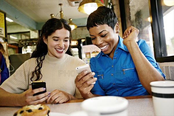 Women using cell phones in restaurant