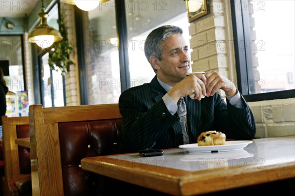 Hispanic businessman having coffee in restaurant