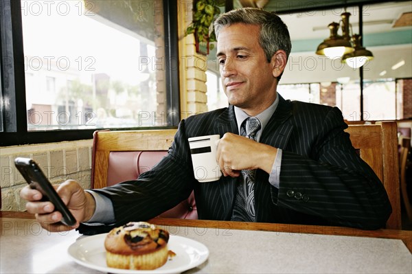 Hispanic businessman using cell phone in restaurant