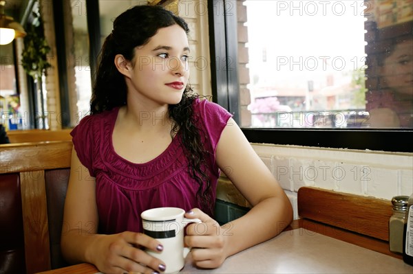 Mixed race woman having coffee in restaurant