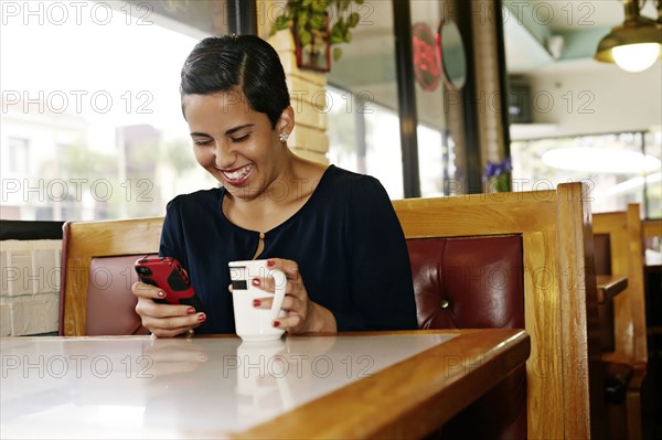 Hispanic businesswoman using cell phone in restaurant