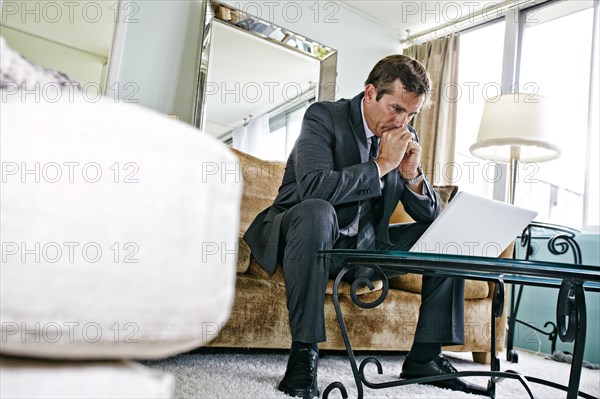 Caucasian businessman using laptop in living room