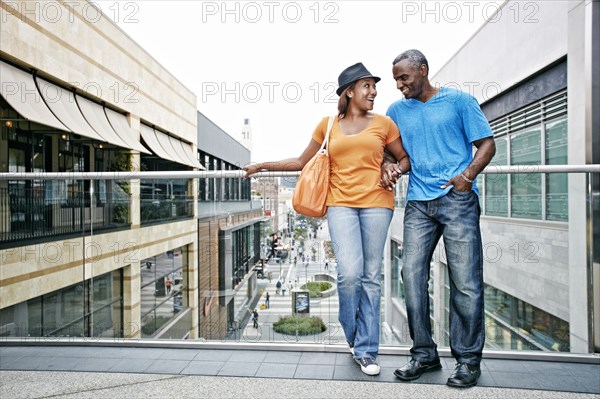 Couple standing on sky bridge at shopping mall