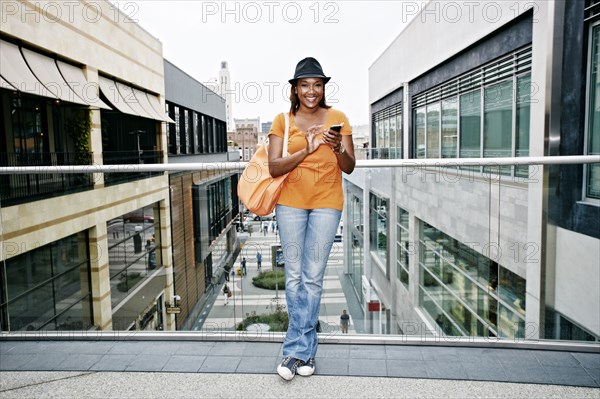 Black woman using cell phone on sky bridge