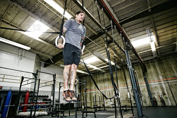 Caucasian man on rings in gym