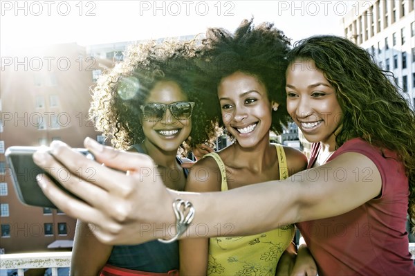 Mixed race women taking self-portrait on urban rooftop