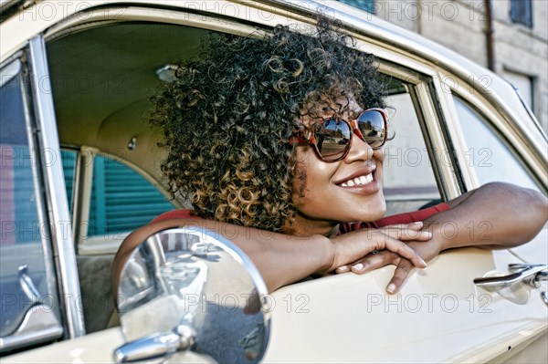 Mixed race woman sitting in vintage car