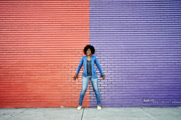Mixed race woman standing by colorful wall