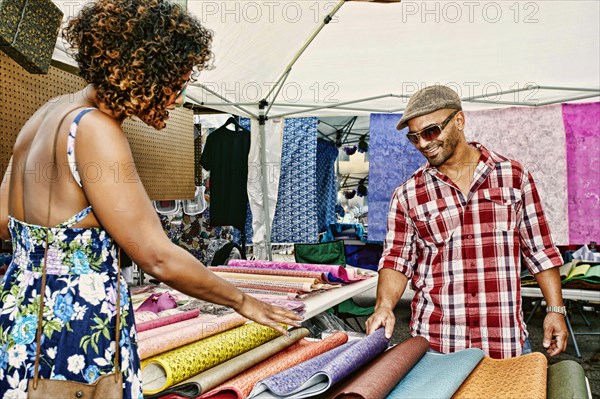 Couple browsing fabrics at flea market