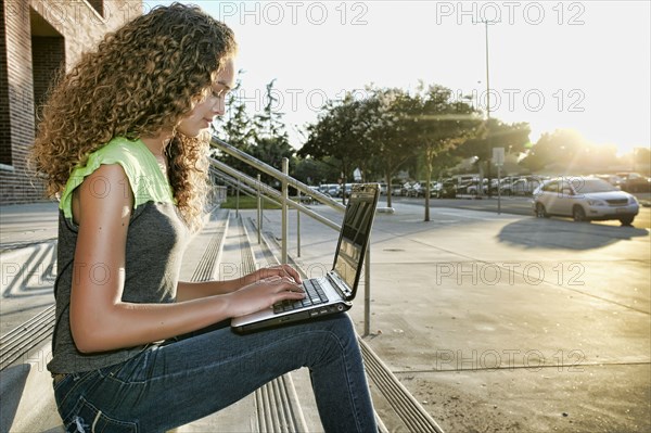 Mixed race girl using laptop on steps