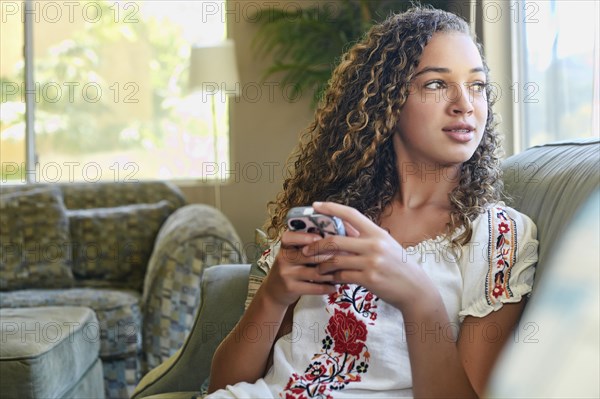 Mixed race girl using cell phone on sofa