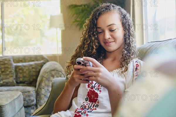 Mixed race girl using cell phone on sofa